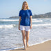 Rack & Cycle women's blue 100% cotton t-shirt with moose graphic and denim shorts, walking on beach.